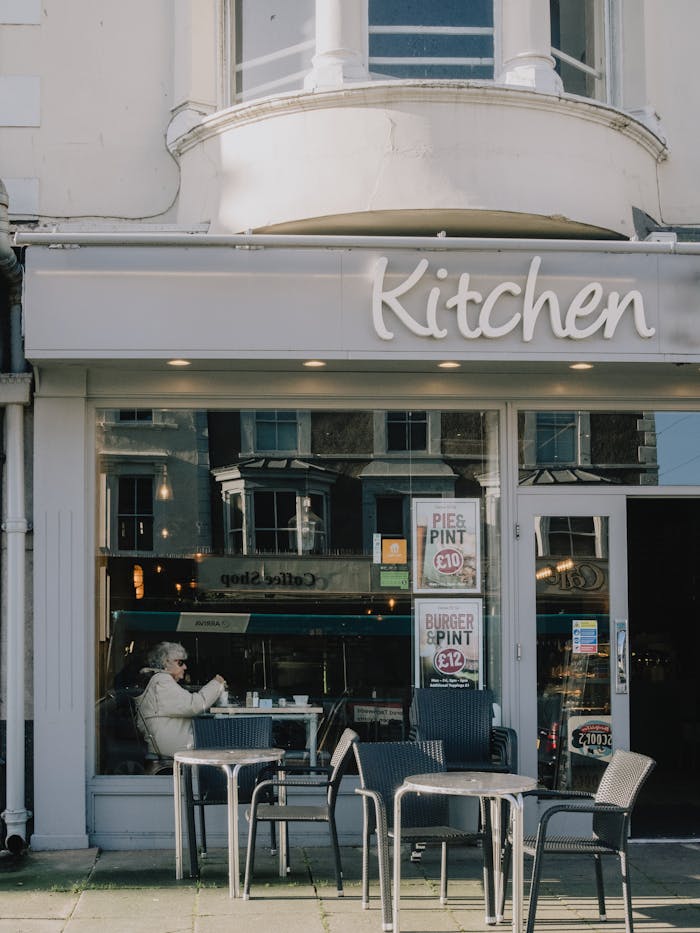 Outdoor view of a café in Llandudno with seating, reflections, and city ambiance.